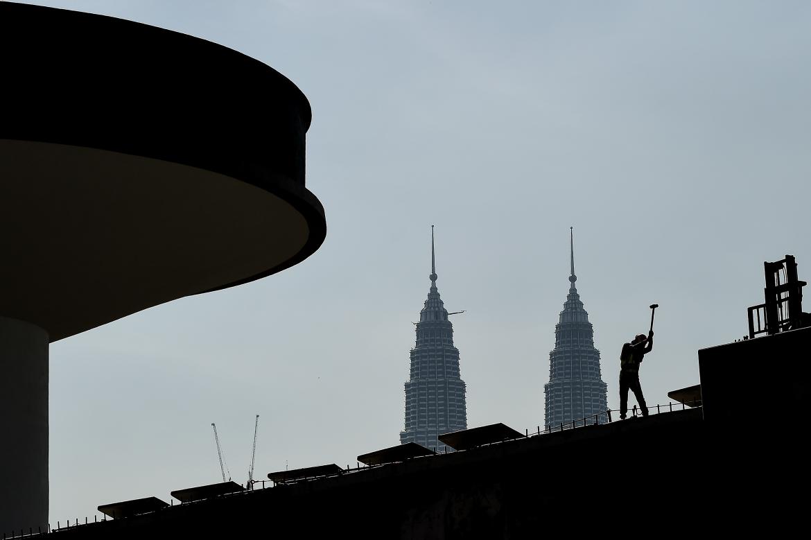 A worker is silhouetted against the Petronas Twin Towers in the Malaysian capital Kuala Lumpur. (AFP)