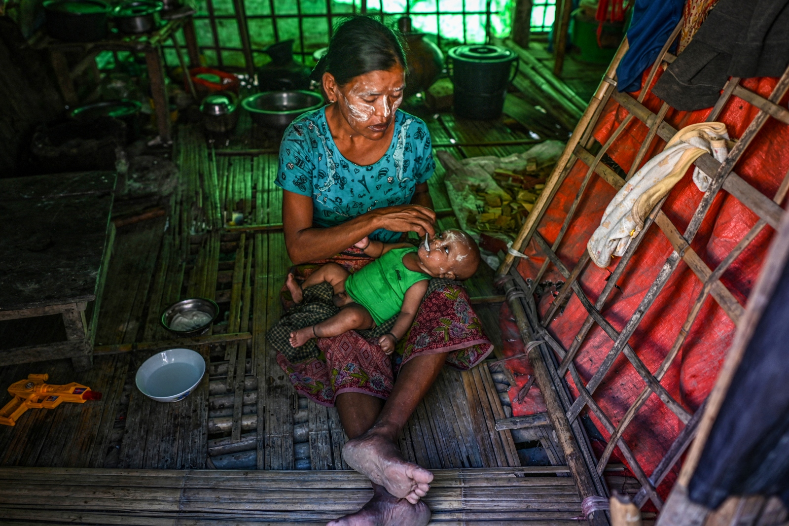 ရခိုင်ပြည်နယ်၊ မြောက်ဦးမြို့ရှိ ပြည်တွင်းနေရပ်စွန့်ခွာသူများ ယာယီခိုလှုံစခန်းတွင် ၂၀၂၁ နိုဝင်ဘာ ၁၉ က အမျိုးသမီးတစ်ဦး မိမိသားငယ်ကို အစာခွံ့နေစဉ်။ (ဓာတ်ပုံ-အေအက်ဖ်ပီ)