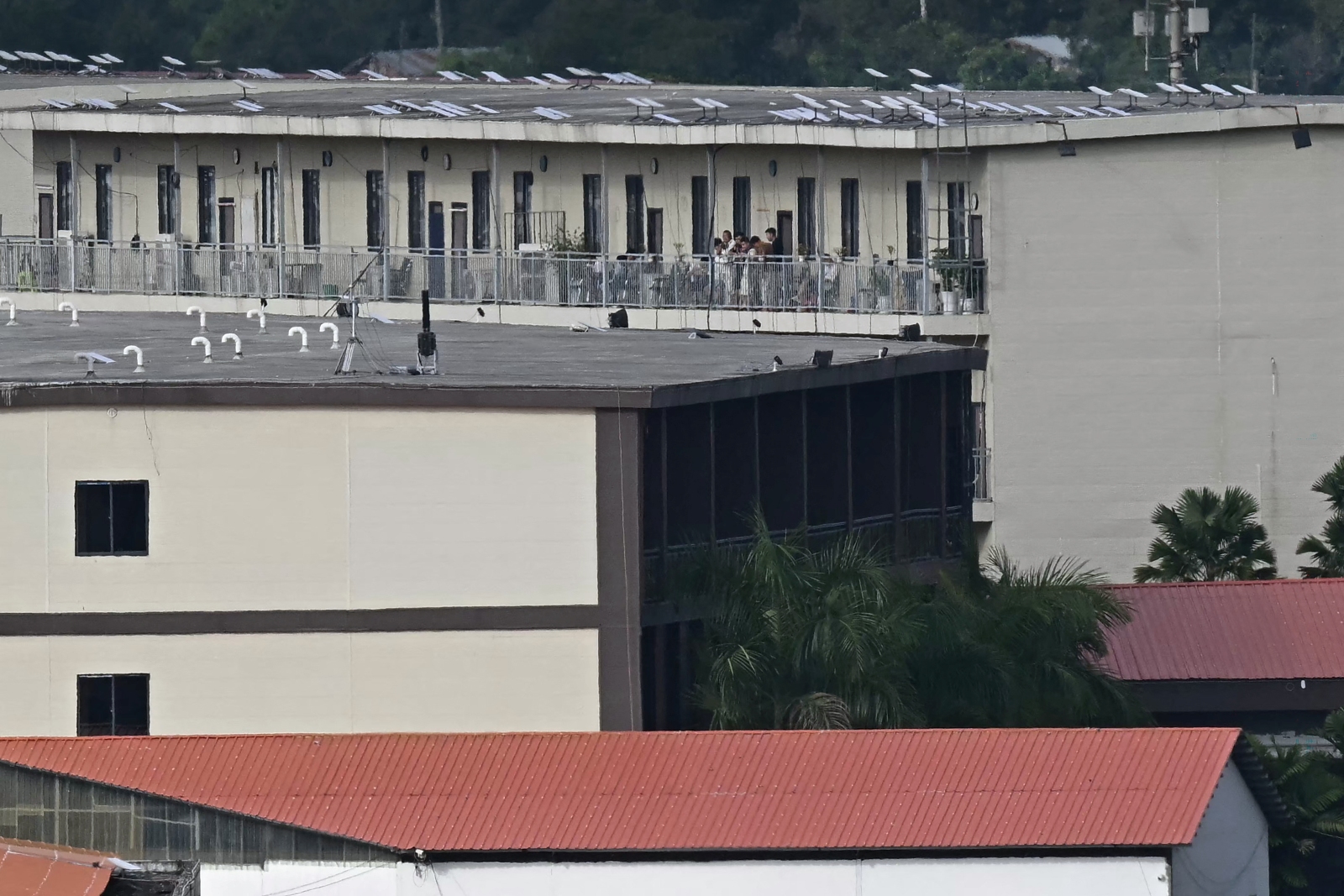 People stand on the balcony of a building with what appears to be Starlink satellite dishes on the roof in the KK Park complex of Kayin State’s Myawaddy Township,  on September 17. (AFP)