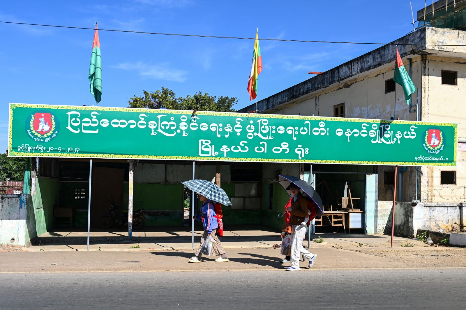 People walk past an election campaign billboard for the military proxy Union Solidarity and Development Party ahead of the junta’s election in northern Shan State’s Nawnghkio town on December 9. (AFP)