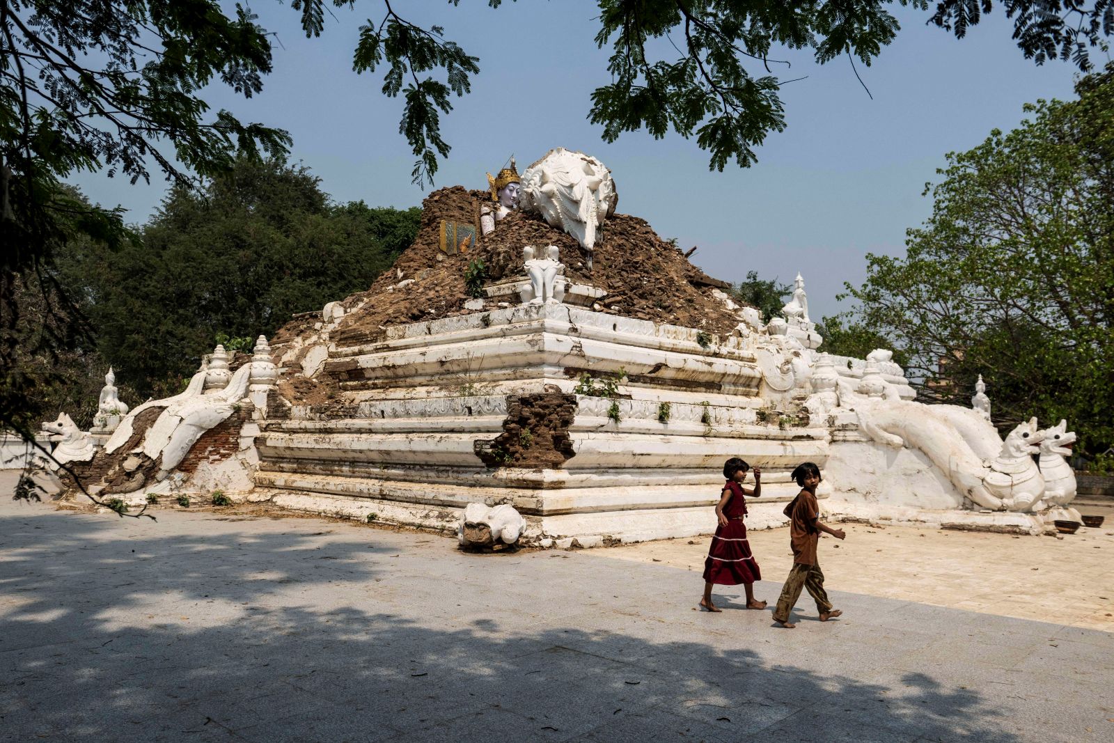 Children walk past the earthquake-damaged Nagayon temple in Mandalay on March 19. (AFP)