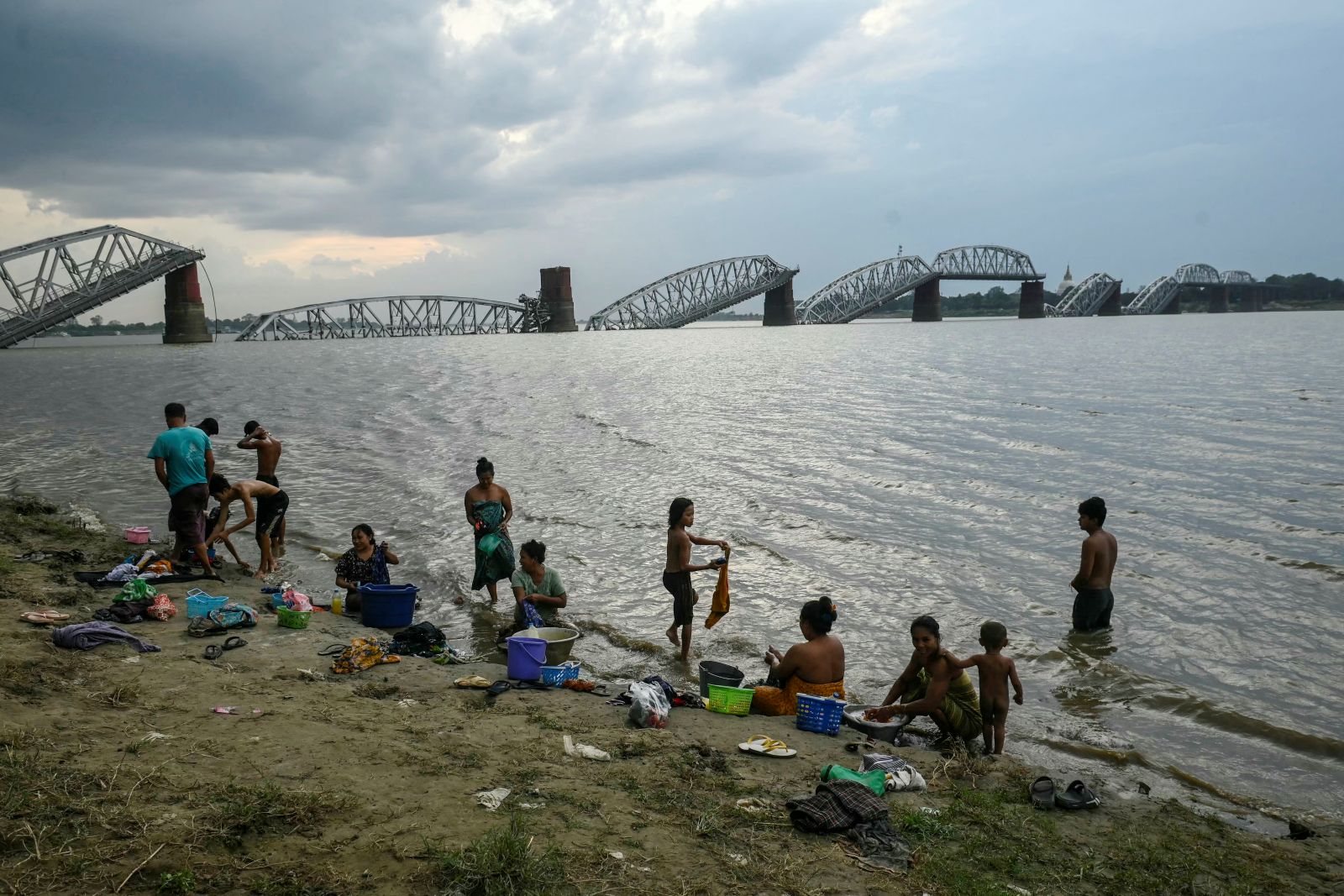 People bathe in the Ayeyarwady River in front of the collapsed Inwa Bridge, near Sagaing town, on April 13, 2025, days after an earthquake struck central Myanmar. (AFP)