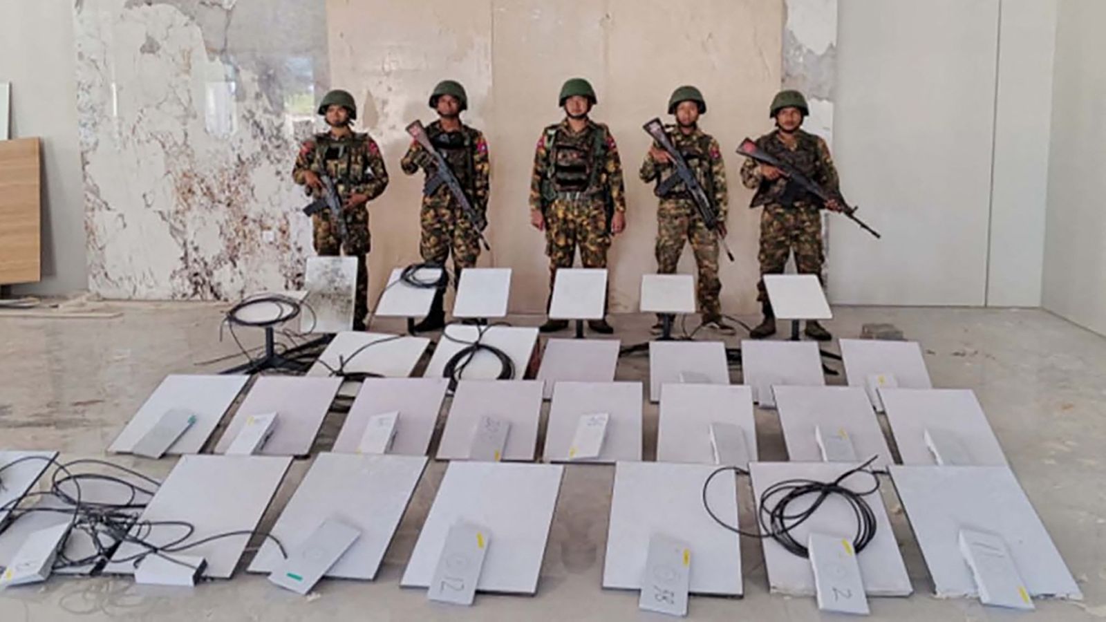 Regime soldiers stand next to Starlink devices seized during a raid on the KK Park cyber scam centre in Kayin State’s Myawaddy Township on October 22, 2025. (AFP)