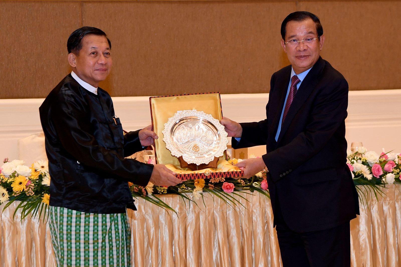 Cambodia’s then-Prime Minister Hun Sen offers a souvenir to junta chief Min Aung Hlaing during a dinner in Nay Pyi Taw on January 7, 2022. (National Television of Cambodia | AFP)