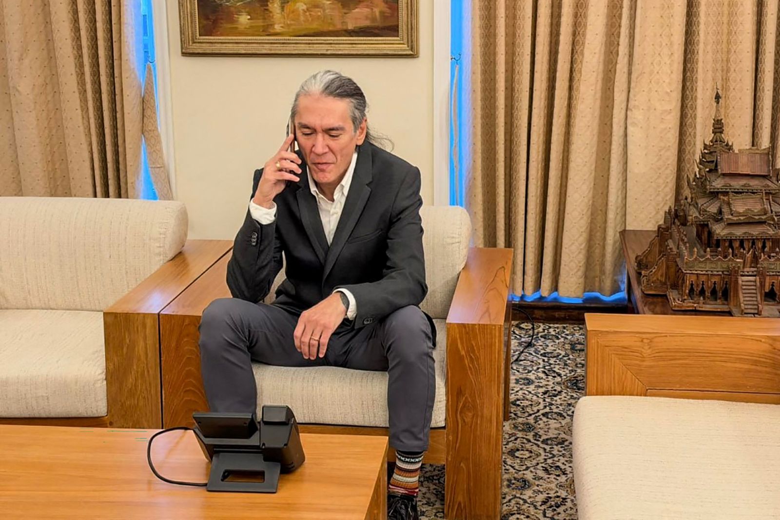 Kim Aris, the younger son of Myanmar's ousted leader Aung San Suu Kyi, speaks on the phone with his mother at the Myanmar Embassy in London on October 22. (Spokesperson for the President of the Republic of the Union of Myanmar | AFP)